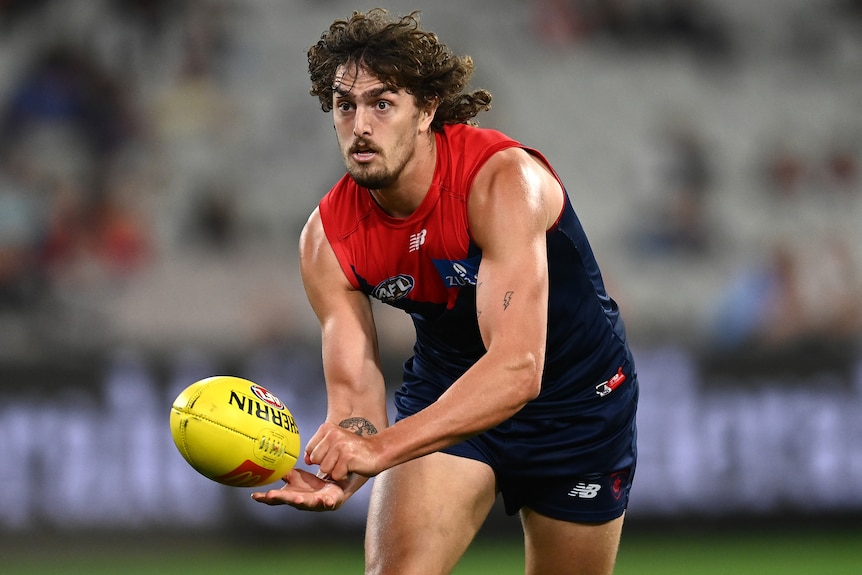 A Melbourne AFL player handballs during a match in 2022.