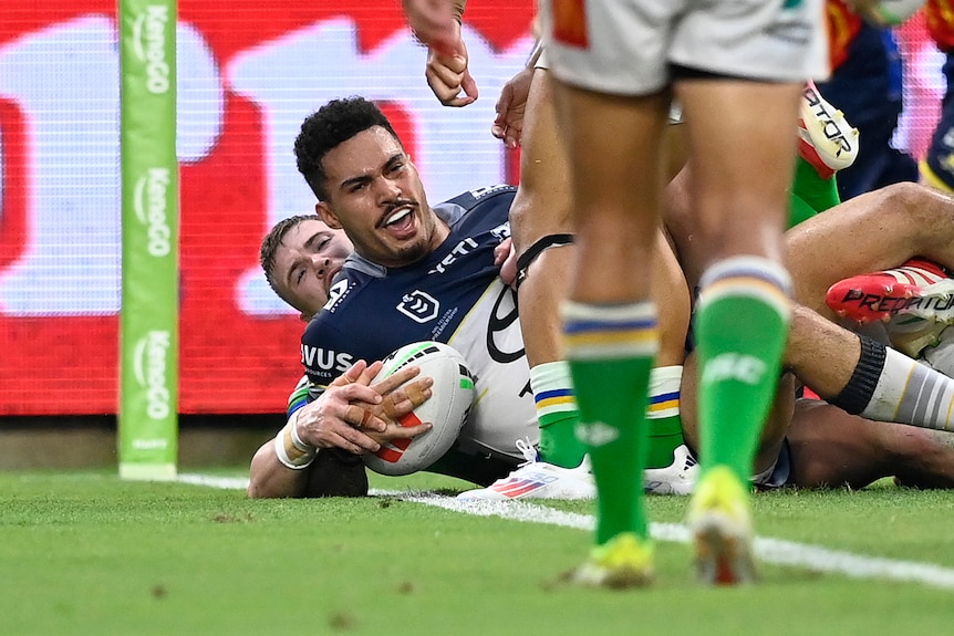 Robert Derby of the Cowboys scores a try, cheering as he lays on the ball