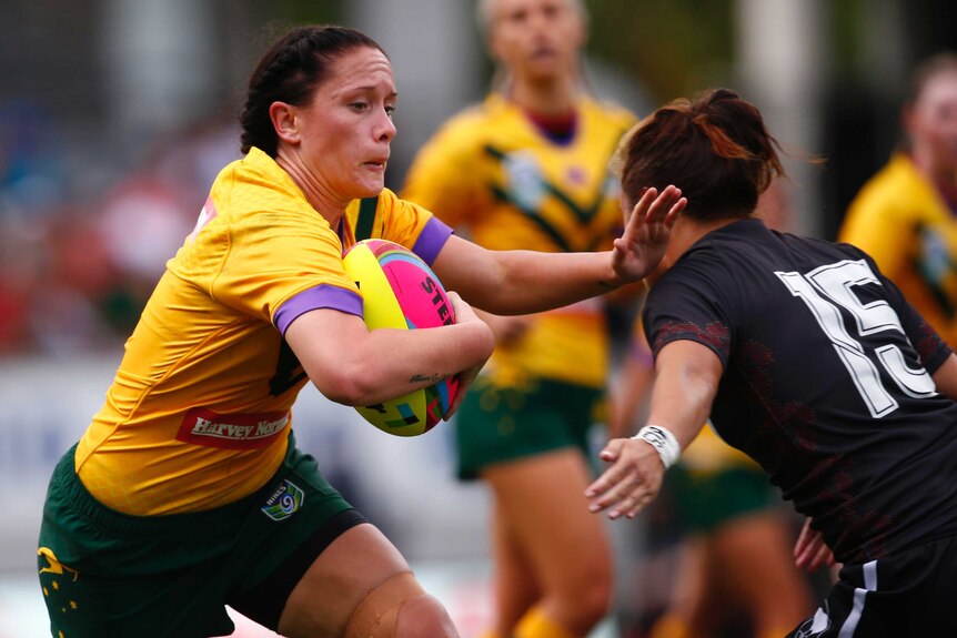 A woman holding a football is tackled by another woman.