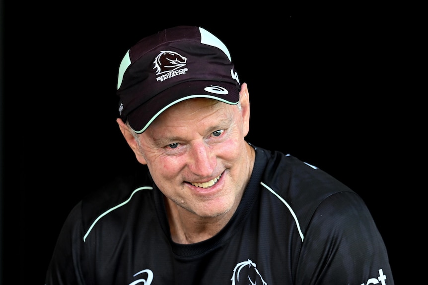 Brisbane Broncos coach Michael Maguire talking to the press, wearing a team shirt and cap
