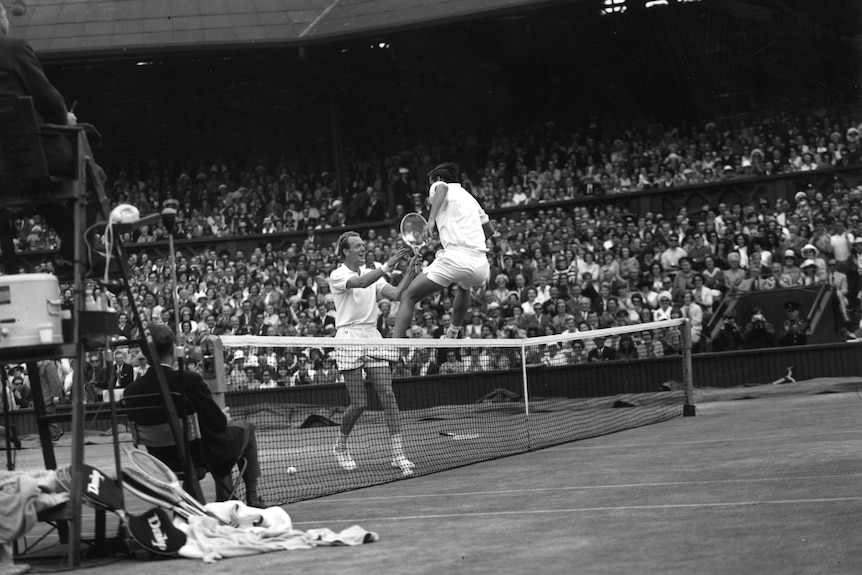 Roy Emerson leaps over the net into the arms of Fred Stolle