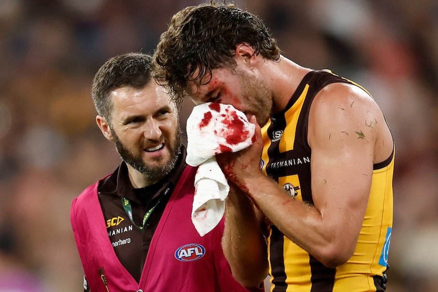 Jack Scrimshaw holds his bloodied nose in a Hawks-Bombers AFL match.