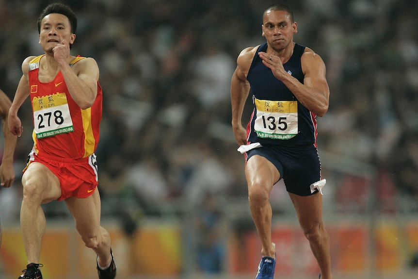 A Chinese man and Aboriginal man captured mid-sprint on an athletics track during an event.