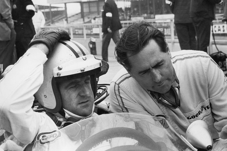 Denny Hulme, sitting in his car, and Jack Brabham, leaning over, at the 1967 Formula 1 British Grand Prix