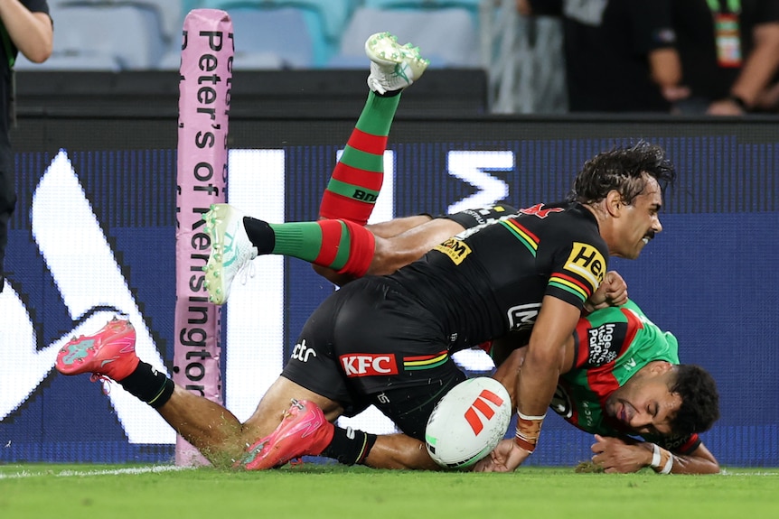 Alex Johnston scores a try as Daine Laurie tackles him during an NRL game.