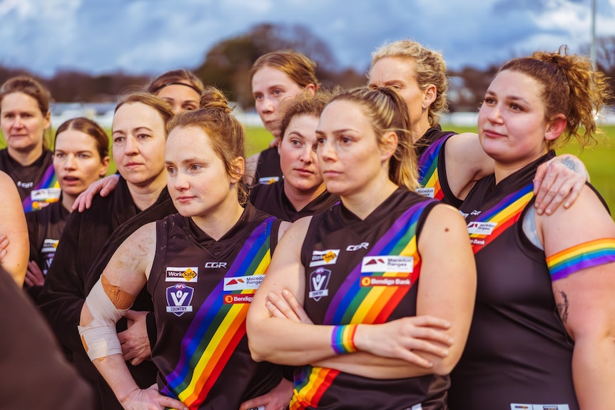 a photo of womens footballers with arms crossed in huddle 