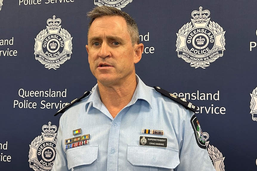 Superintendent Craig Hawkins stands in front of a wall with Queensland police service written on it while speaking to media.