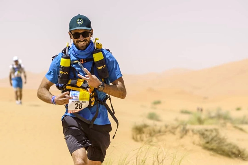 A man in athletic gear runs through a desert.