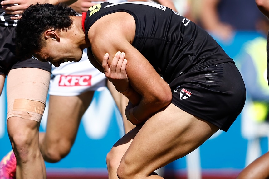 Mitch Owens clutching his left shoulder after being injured in an AFL preseason match.