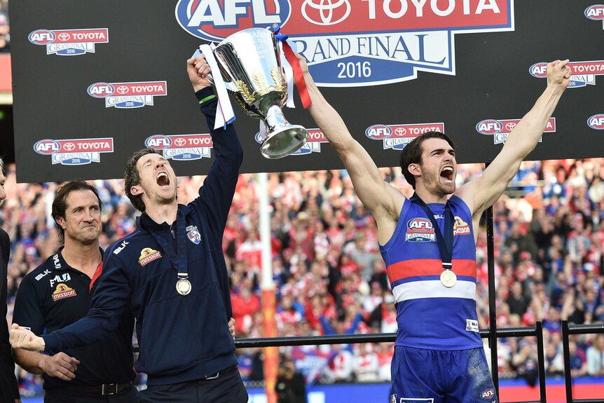 Two men hold up their hands in triumph after winning a football match 
