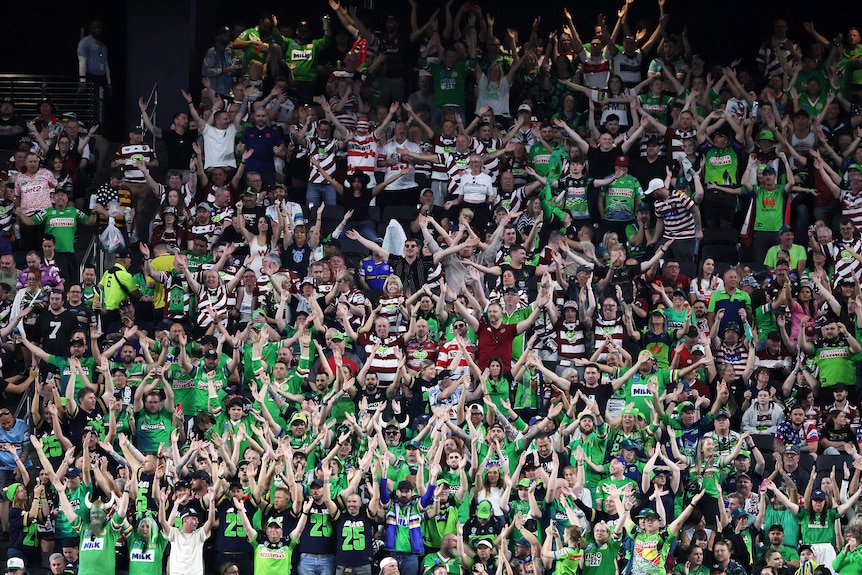 A group of fans celebrate a try in a rugby league match