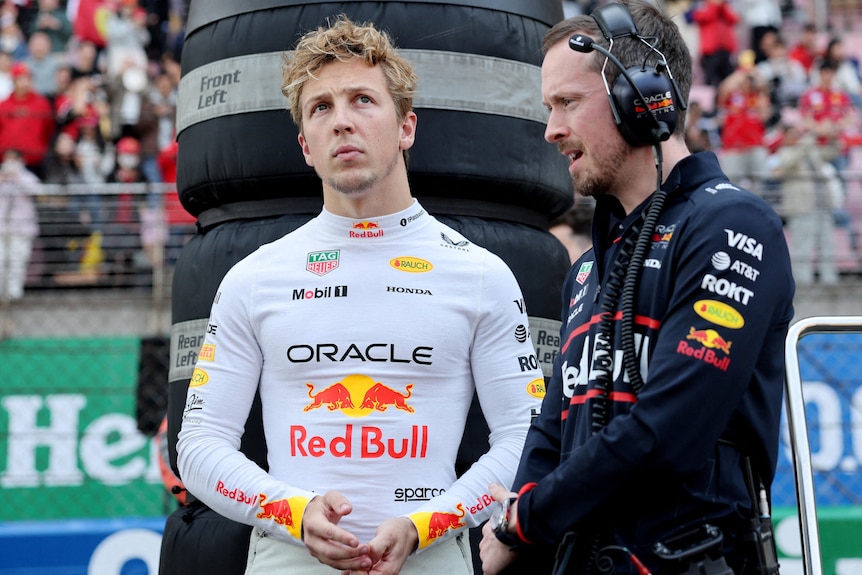 An F1 driver standing on the grid with his race engineer before a race