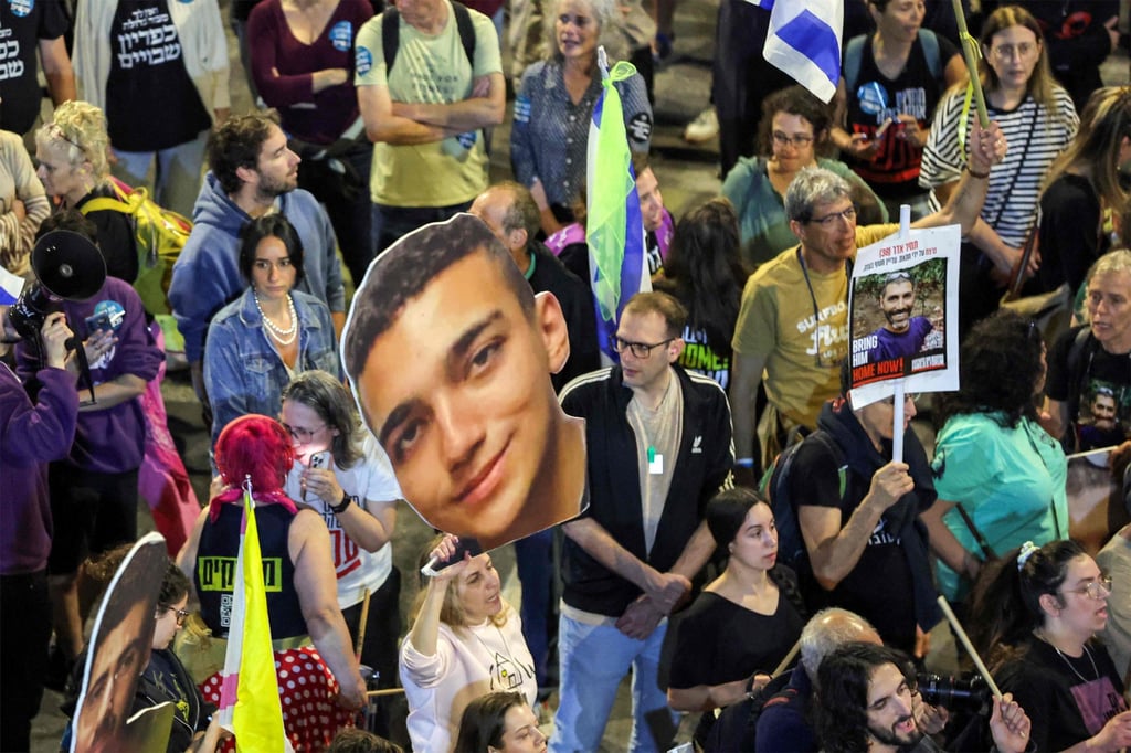 A demonstrator holds a sign showing the face of Israeli hostage Edan Alexander (centre) during a protest outside the Israeli Defence Ministry headquarters in Tel Aviv in March. Photo: AFP A demonstrator holds a sign showing the face of Israeli hostage Edan Alexander (centre) during a protest outside the Israeli Defence Ministry headquarters in Tel Aviv in March. Photo: AFP