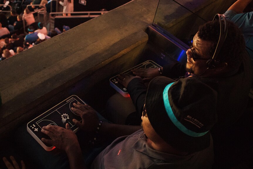 A high angle shot of two people sitting down with their hands on model, black basketball courts on their laps