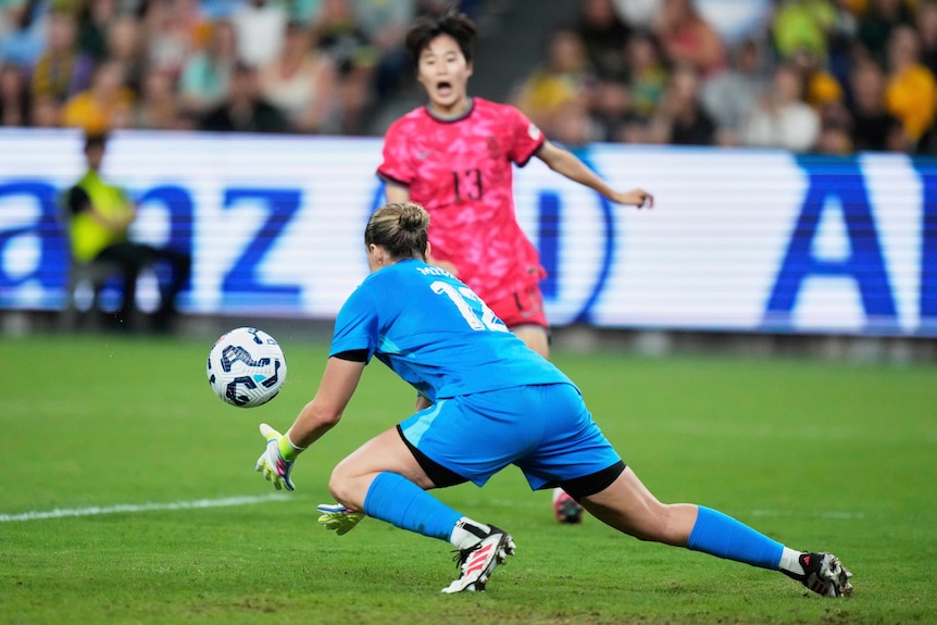 Matildas goalkeeper Meagan Ticah dives forward with hands out to grab the ball during an international.