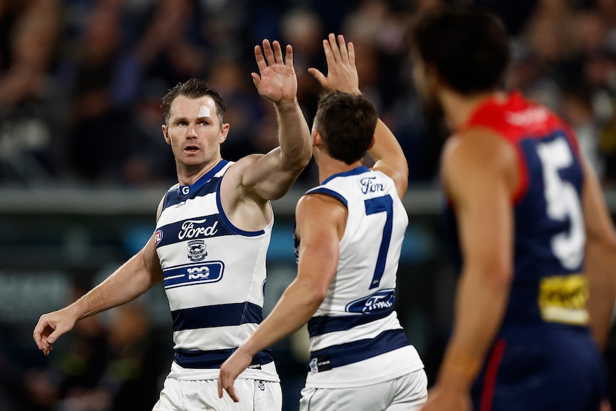 Patrick Dangerfield high-fives Shaun Mannagh as Christian Petracca watches on
