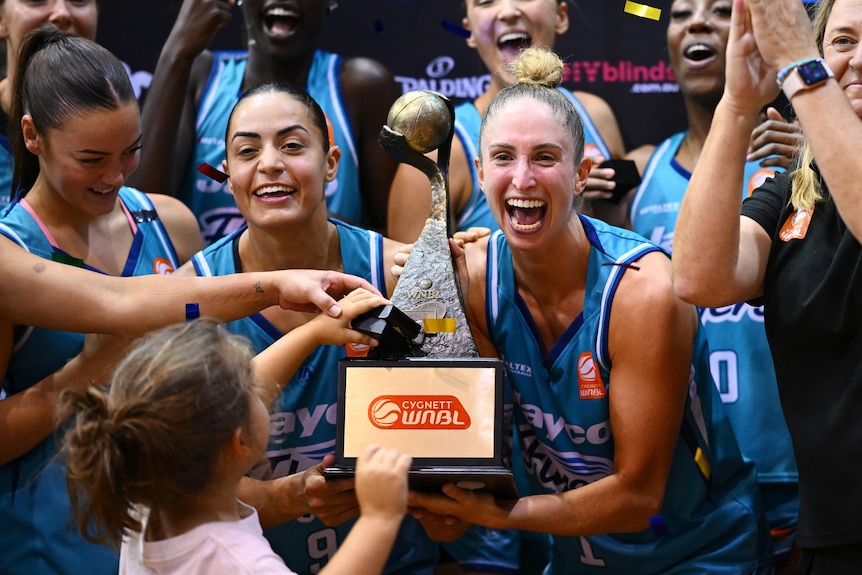 Southside Flyers players Maddi Rocci and Bec Cole hold the WNBL trophy and smile