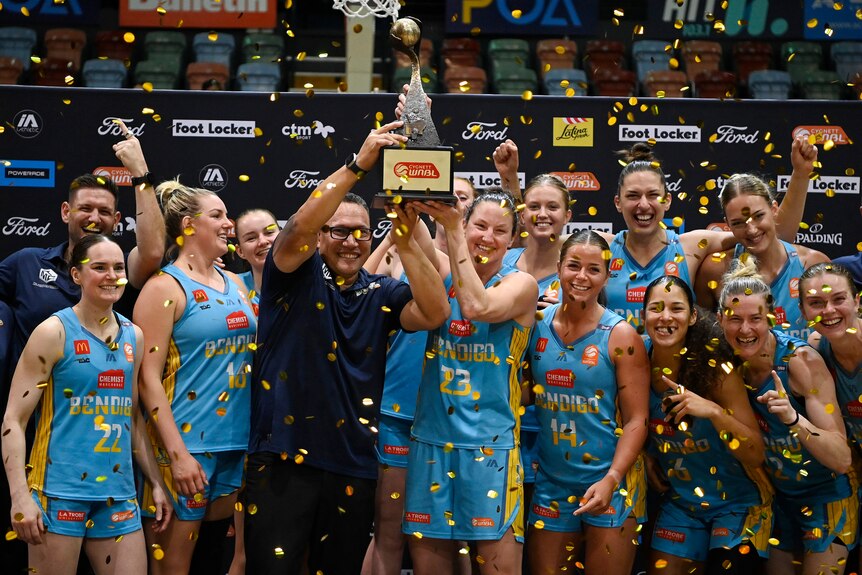 Bendigo Spirit players and coaches celebrate with the WNBL trophy and confetti