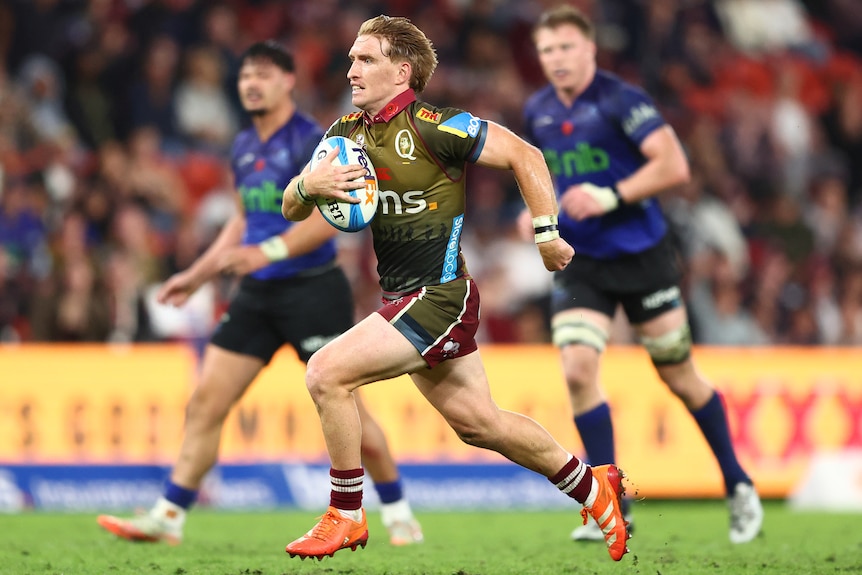 Tate McDermott running with the ball for the reds against the Blues.