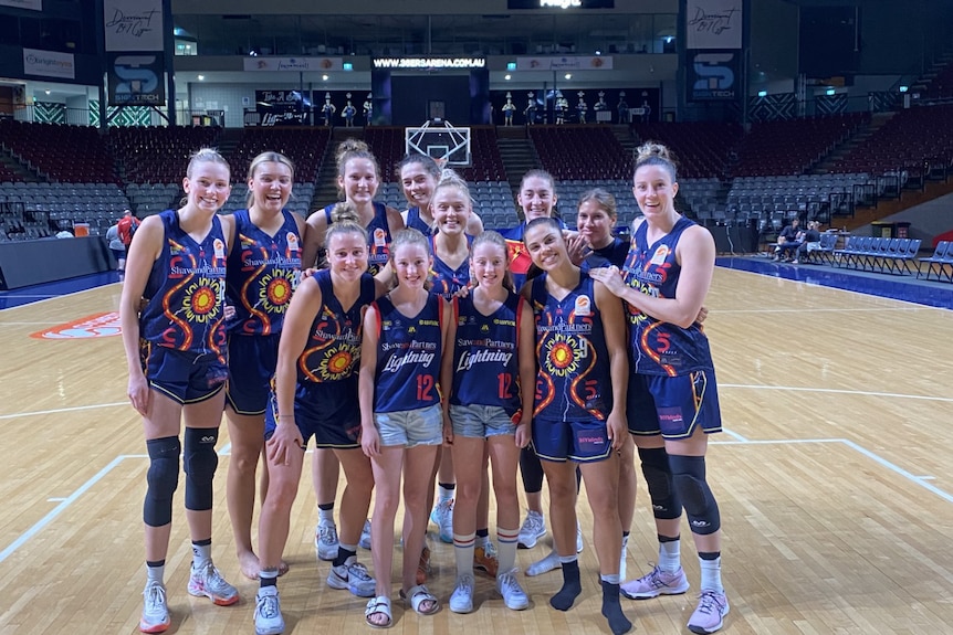A group of females stand on a basketball court.