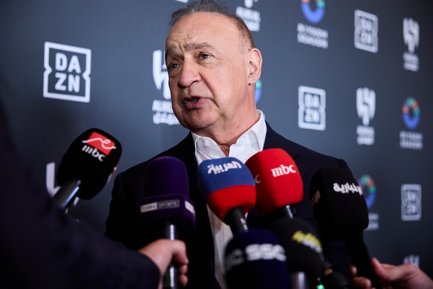A middleaged man fronts a press conference with DAZN branding behind him