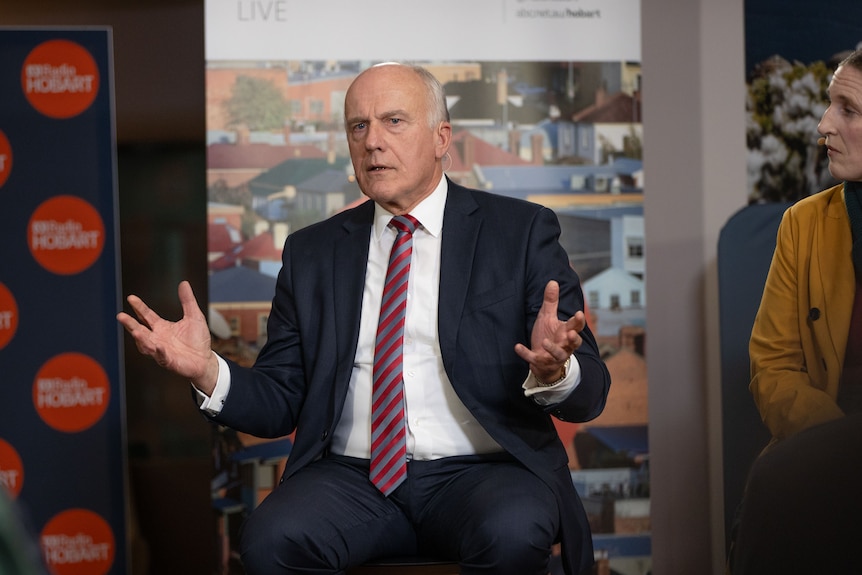 A man in a suit speaking on a panel.