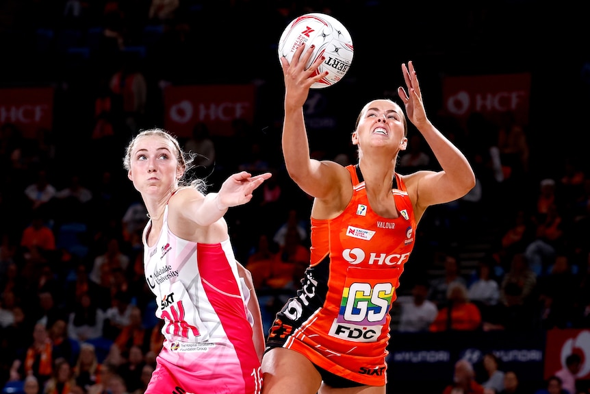 Two players stick their arms out to try and contest the ball
