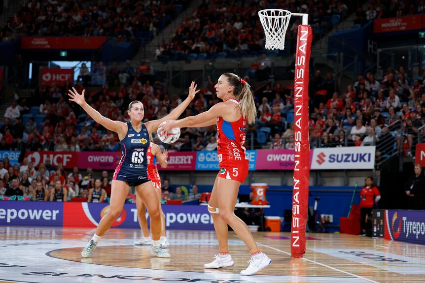 A player holds the ball and assesses where to through it next as she is defended by the opposition