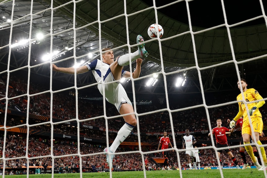 Tottenham Hotspur's Micky van de Ven lifts his foot to clear the ball from the goal