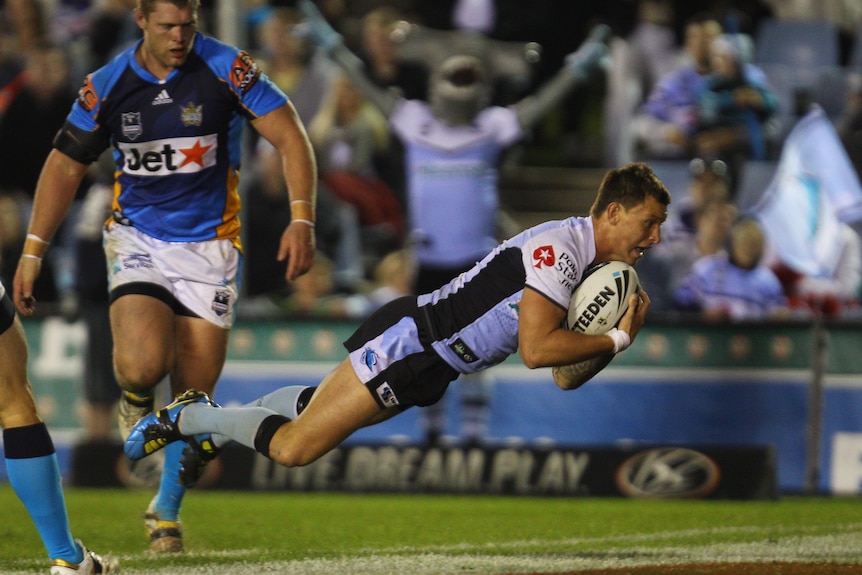 A man dives over to score a try in a rugby league match 