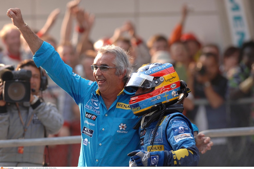 An F1 team boss, hugging his driver with one arm, and punching his fist in the air with the other arm