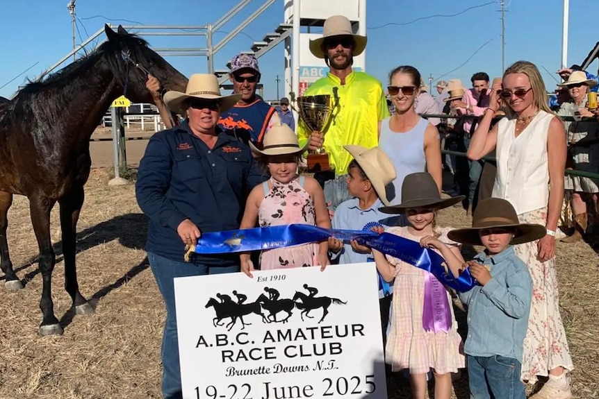 A group of people and a horse celebrating a winning run.
