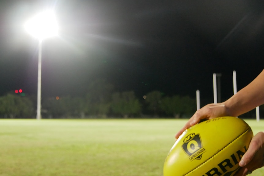 A photo of an AFL ball at training on an evening.
