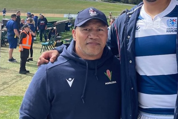Samoan man Onehunga Mata'uiau wears a navy blue jumper and hat standing on the sidelines of a stadium