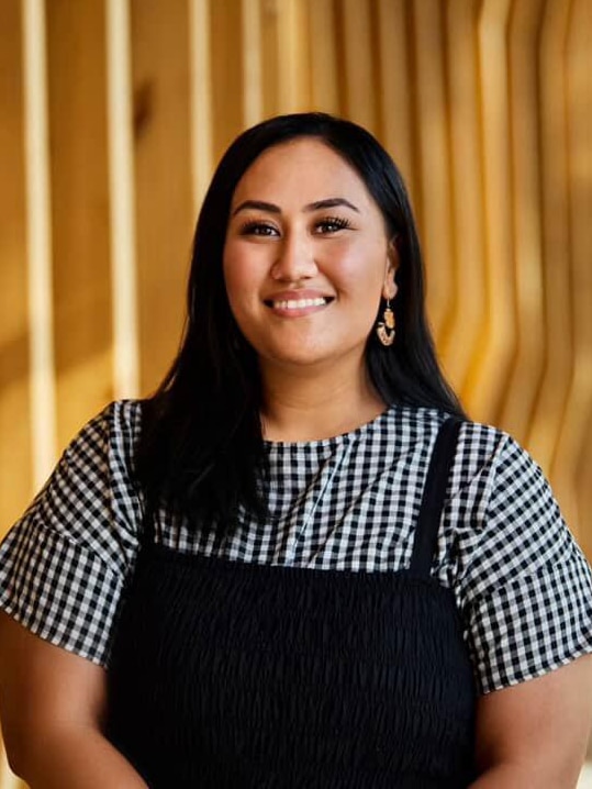 A Samoan woman with short black hair smiling in a professional photoshoot