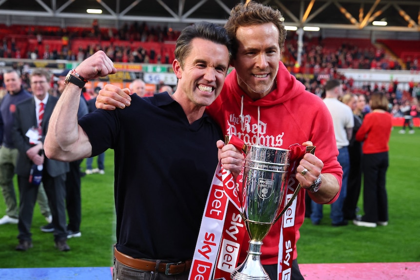 Rob McElhenney and Ryan Reynolds celebrate with a trophy after being promoted to the Championship.