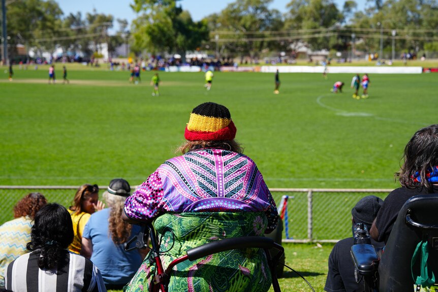 A woman sits in front of a sporting ground