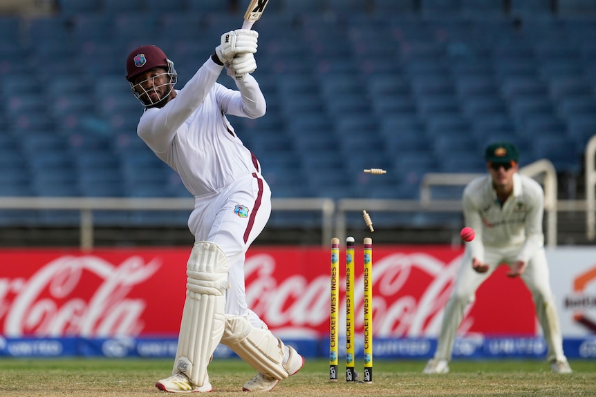 West Indies batter Mikyle Louis completes his swing as the cricket ball hits his stumps.