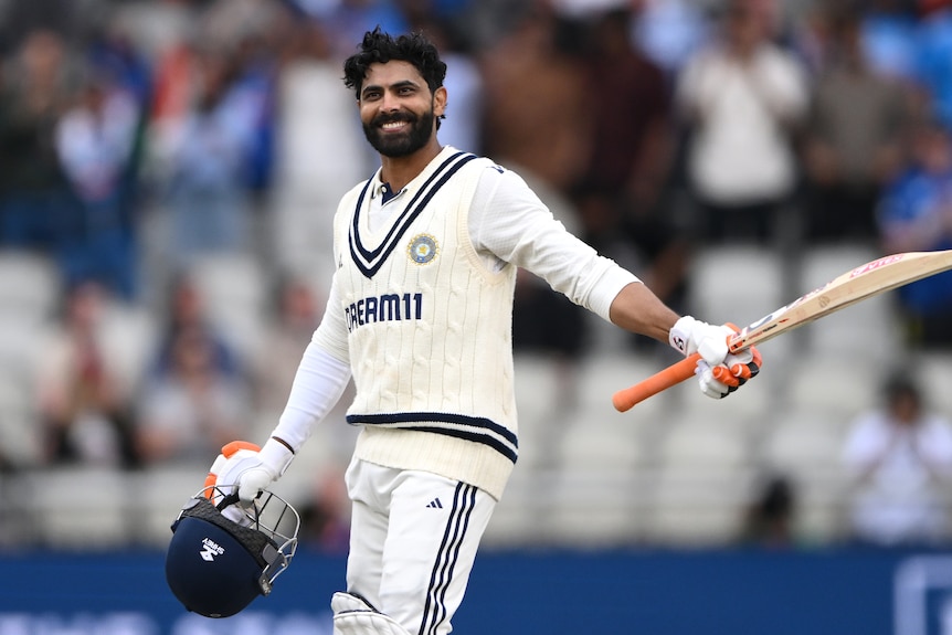 Ravindra Jadeja holds his bat and helmet in celebration