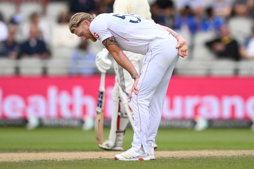 England bowler Ben Stokes puts his hand behind his back while leaning forward during a Test match.