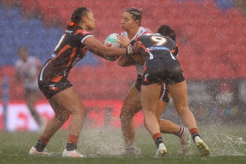 Jocelyn Kelleher of the Roosters is tackled during the round five NRLW match between Wests Tigers as rain falls.