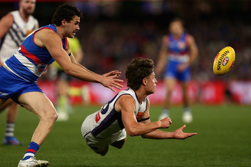 Dockers player Neil Erasmus dives after delivering a handball.