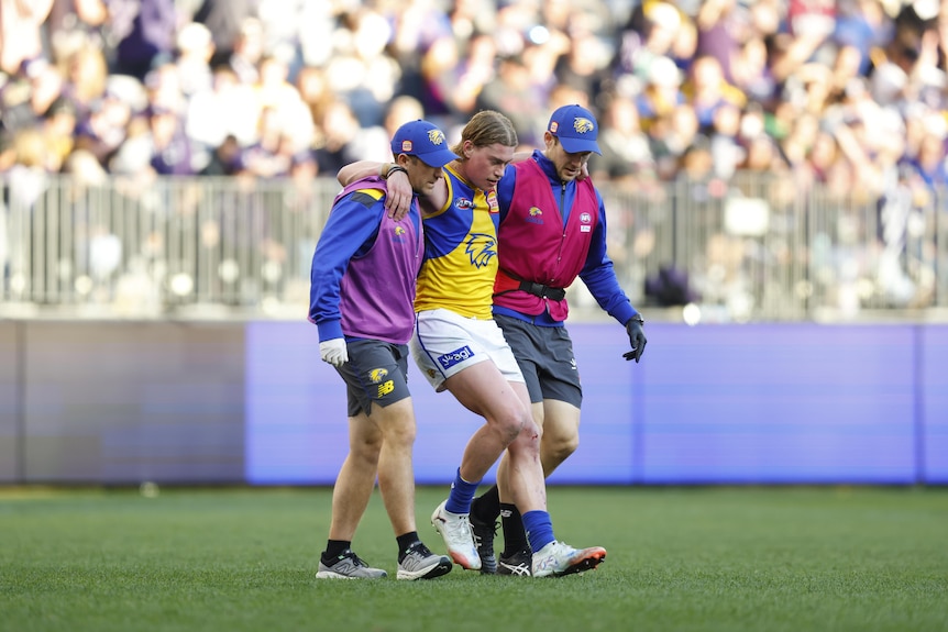 Harley Reid is helped by two eagles staffers off the pitch with an apparent leg injury.