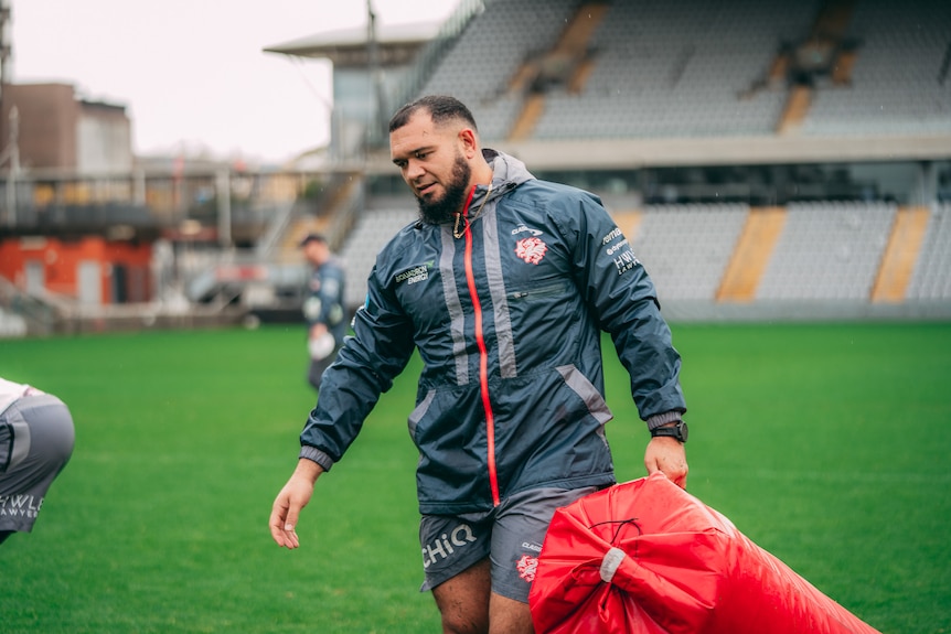 A man carries a tackle pad during a rugby league training session