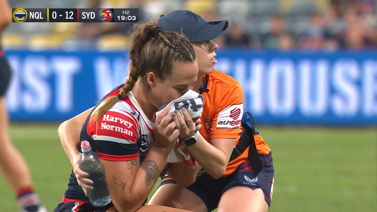 Isabelle Kelly holds a towel over her mouth during a Roosters NRLW game.
