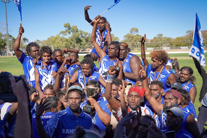 A football team wearing medals and cheering as they wave club flags.