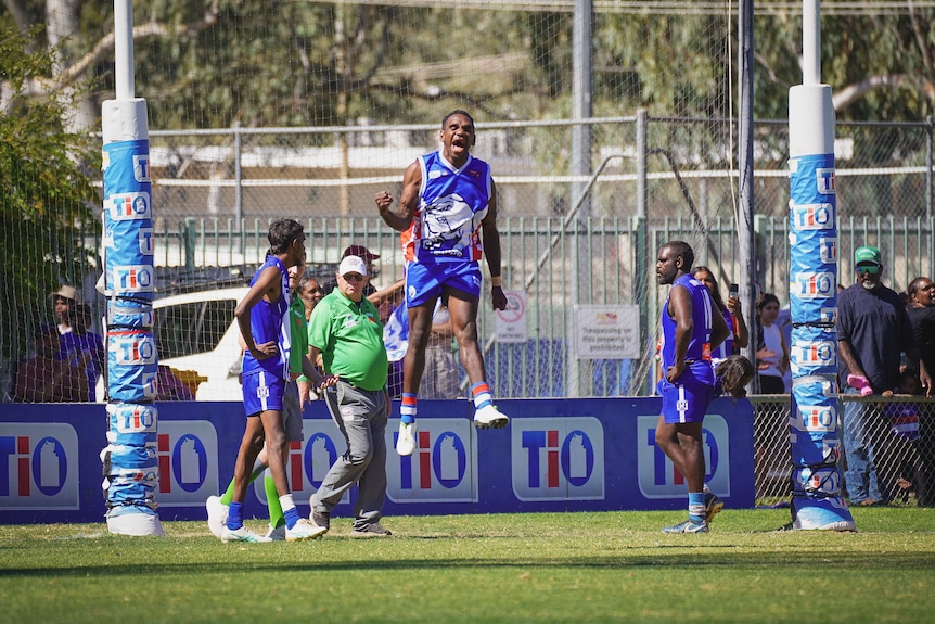 A football player jumping in the air and cheering after scoring a goal.