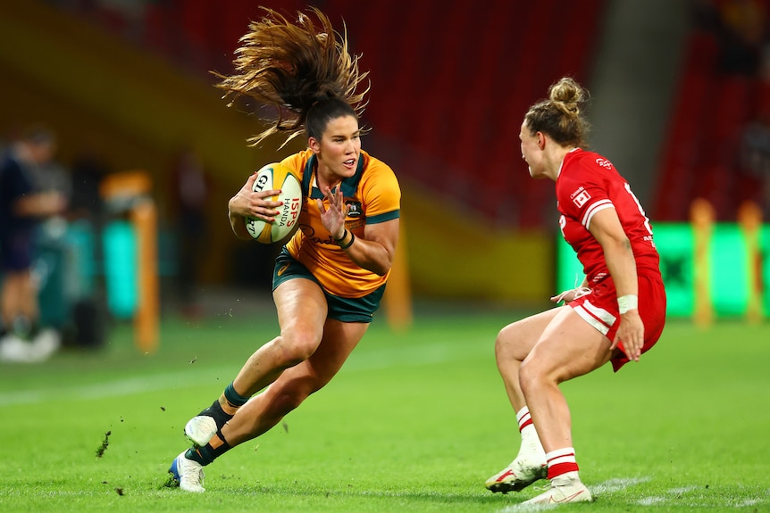 Wallaroos player Charlotte Caslick is running with the ball in one hand and palm up on other hand.
