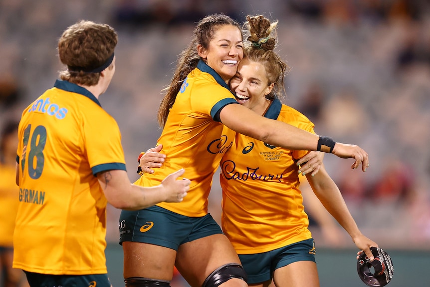 Wallaroos celebrate winning a match by embracing in a hug