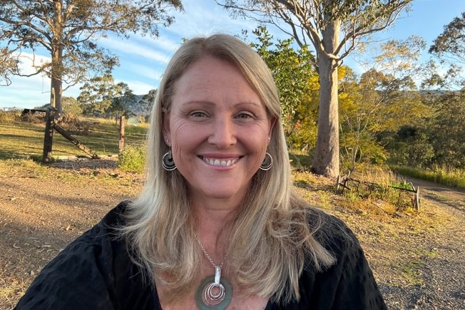 Kirralie Smith smiling with bushland in the background. 